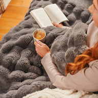 Woman enjoys coffee and a book under a Grey Hygge Days Throw