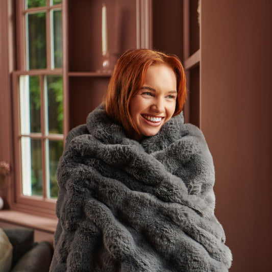 Woman drapes herself in a grey super soft hygge days throw